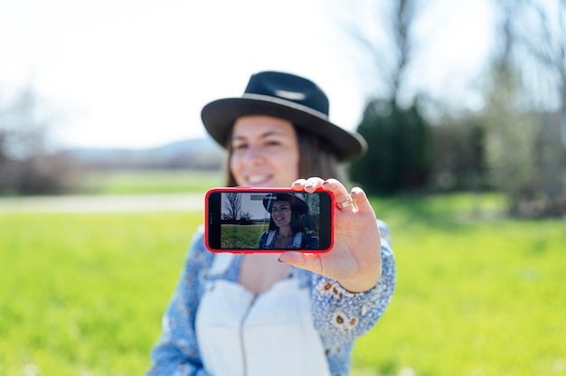 Mooie jonge vrouw die een selfie maakt op het veld