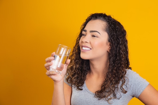 Mooie jonge vrouw die een vers glas water drinkt