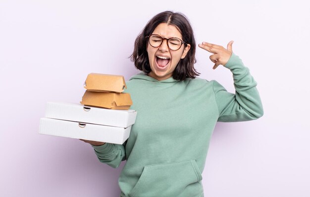 Mooie jonge vrouw die er ongelukkig en gestrest uitziet, zelfmoordgebaar dat een pistoolteken maakt. fastfood afhaalconcept