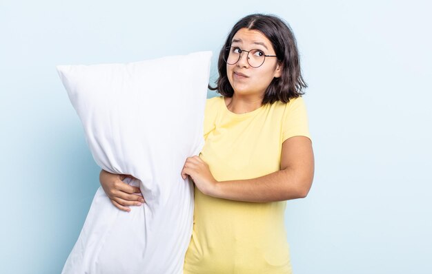 Mooie jonge vrouw die haar schouders ophaalt, zich verward en onzeker voelt. bedconcept