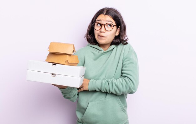 Mooie jonge vrouw die haar schouders ophaalt, zich verward en onzeker voelt. fastfood afhaalconcept