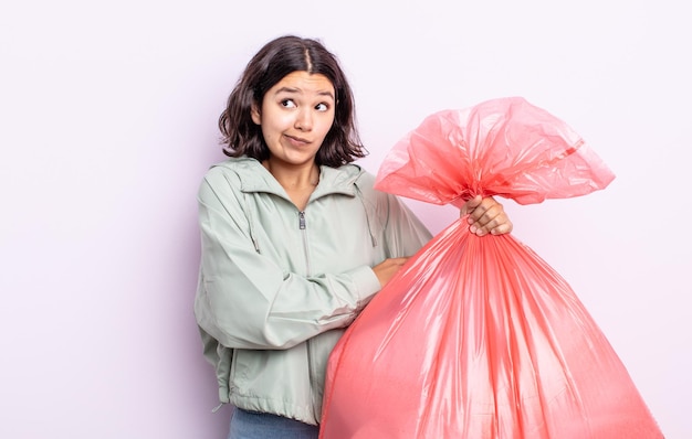 Mooie jonge vrouw die haar schouders ophaalt, zich verward en onzeker voelt. vuilniszak concept