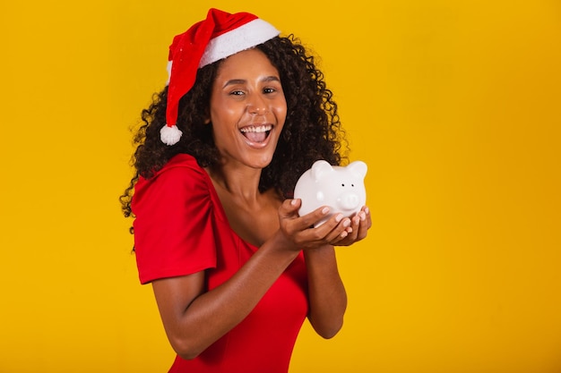 Mooie jonge vrouw die het spaargeld van een spaarvarken opneemt om de kerstcadeautjes te kopen. Jonge vrouw met een spaarvarken