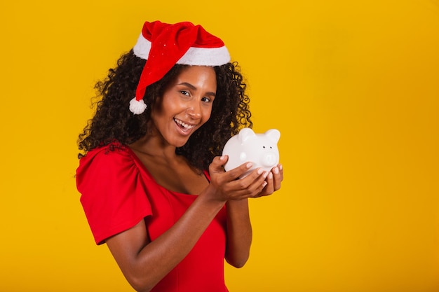 Mooie jonge vrouw die het spaargeld van een spaarvarken opneemt om de kerstcadeautjes te kopen. Jonge vrouw met een spaarvarken