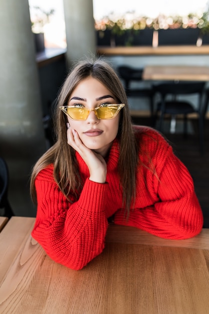 Mooie jonge vrouw die in het café zit