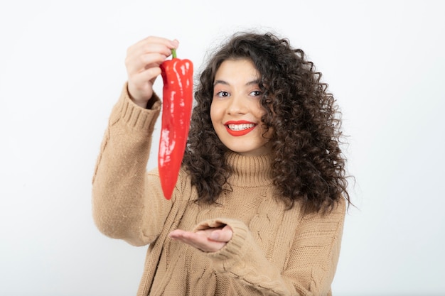 Mooie jonge vrouw die in rode lippenstift rode Spaanse peperpeper houdt.