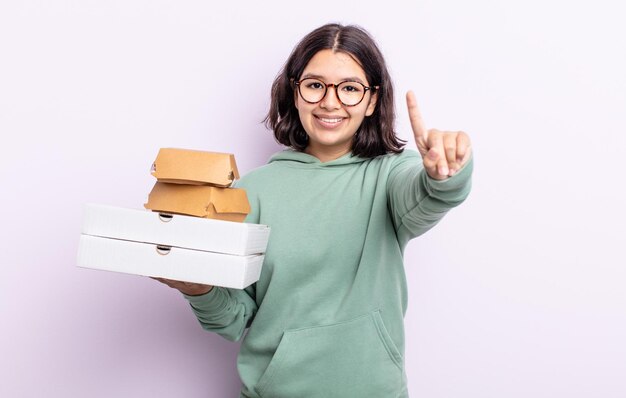 Mooie jonge vrouw die lacht en er vriendelijk uitziet, met nummer één. fastfood afhaalconcept