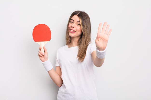 Mooie jonge vrouw die lacht en er vriendelijk uitziet, met nummer vier. pingpongconcept