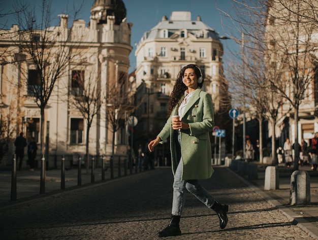 Mooie jonge vrouw die muziek luistert met een koptelefoon op straat