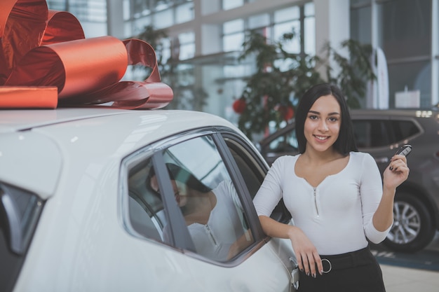 Mooie jonge vrouw die nieuwe auto koopt bij het handel drijven