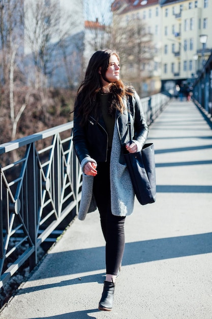 Mooie jonge vrouw die op een zonnige dag over de voetgangersbrug loopt