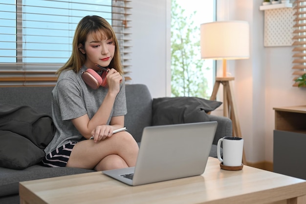 Mooie jonge vrouw die op internet surft op de computer die in het weekend online nieuws leest
