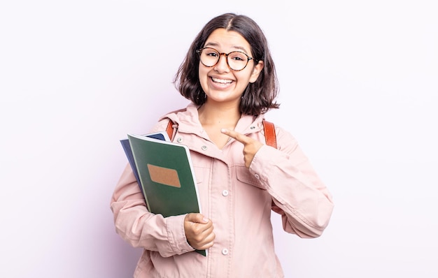 Mooie jonge vrouw die opgewonden en verrast kijkt en naar de zijkant wijst. student met boeken concept