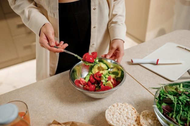 Mooie jonge vrouw die plantaardige veganistische salade in de keuken bereidt Gezonde voeding en dieetconcept levensstijl Thuis koken