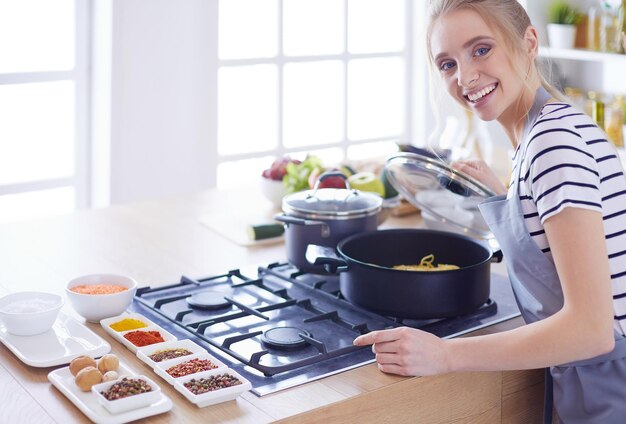 Mooie jonge vrouw die thuis in de keuken kookt