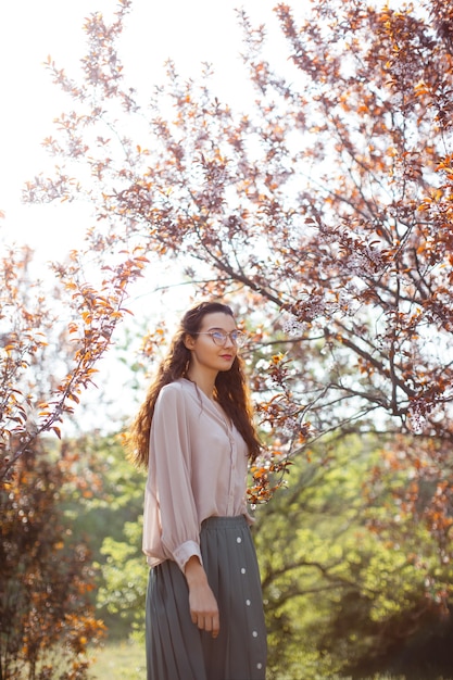 Mooie jonge vrouw die tijdens het seizoen van de kersenbloesem geniet van een zonnige lentedag in een park