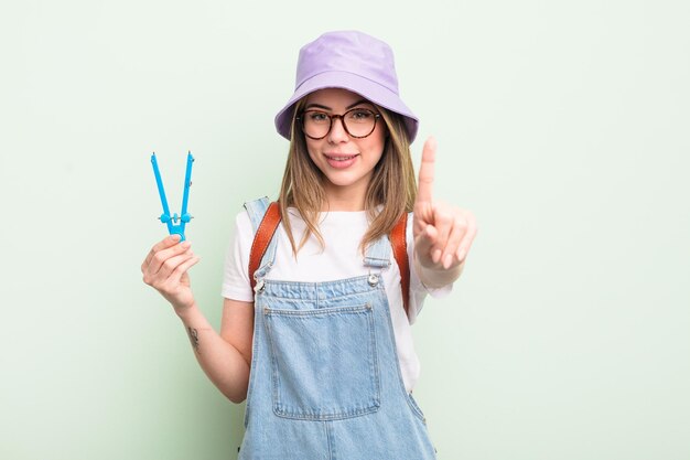 Mooie jonge vrouw die trots en zelfverzekerd glimlacht en nummer één maakt. studentenconcept