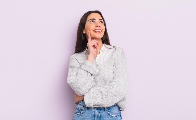 Mooie jonge vrouw die vrolijk lacht en dagdroomt of twijfelt, opzij kijkend