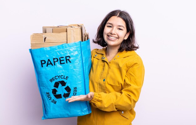 Mooie jonge vrouw die vrolijk lacht, zich gelukkig voelt en een concept toont. papier recycle concept