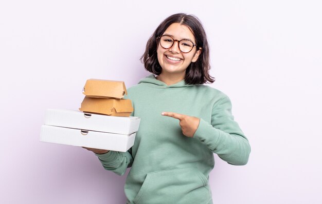 Mooie jonge vrouw die vrolijk lacht, zich gelukkig voelt en naar de zijkant wijst. fastfood afhaalconcept