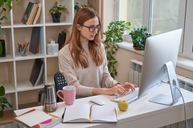 Mooie jonge vrouw die werkt terwijl ze naar het computerscherm kijkt