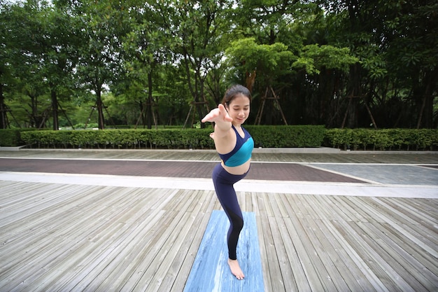 Mooie jonge vrouw die yoga beoefent op houten terras