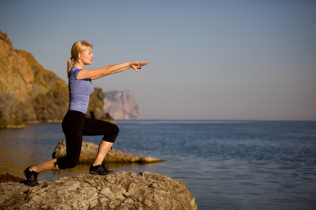 Mooie jonge vrouw die yoga op een steen doet