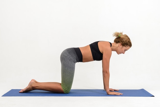 Mooie jonge vrouw die yoga op wit doet