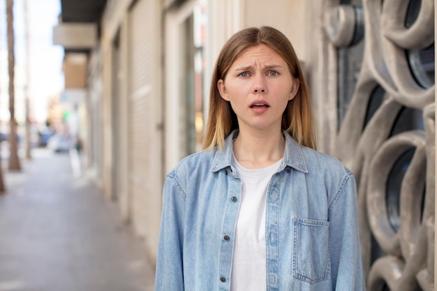 Foto mooie jonge vrouw die zich doodsbang en geschokt voelt met de mond wijd open van verbazing