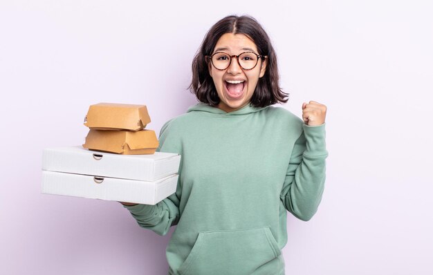 Mooie jonge vrouw die zich geschokt voelt, lacht en succes viert. fastfood afhaalconcept