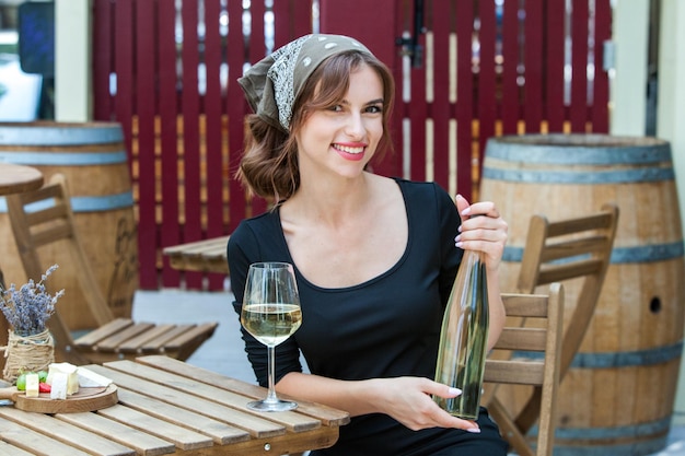 Foto mooie jonge vrouw drinkt witte wijn op het terras van een restaurant ontspant na het werk