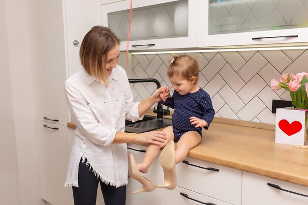 Mooie jonge vrouw en haar charmante dochtertje glimlachen in het interieur van de keuken