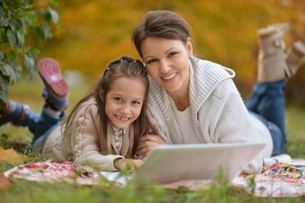 Mooie jonge vrouw en meisje met behulp van laptop in park