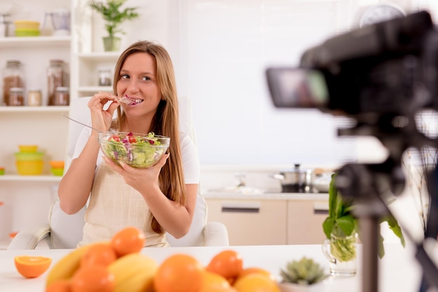 Mooie jonge vrouw filmt haar bloguitzending over gezond eten thuis.