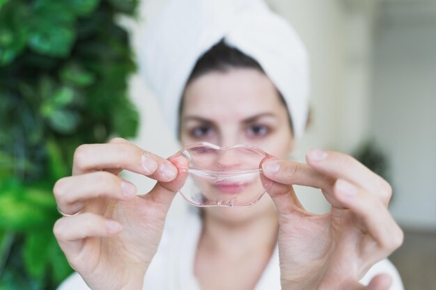 Mooie jonge vrouw gebruikt collageen hydrogel roze lip patch gelmasker voor glad, vochtig, opgezwollen zachte pruilmonden witte badjas handdoekself skin careanti leeftijdsbehandeling voor rimpels in de badkamer thuis