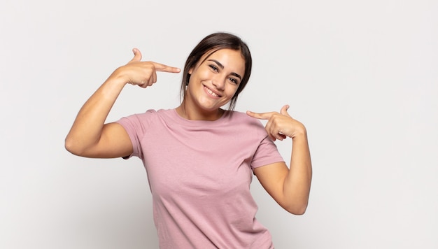 Mooie jonge vrouw glimlachend vol vertrouwen wijzend op eigen brede glimlach, positieve, ontspannen, tevreden houding