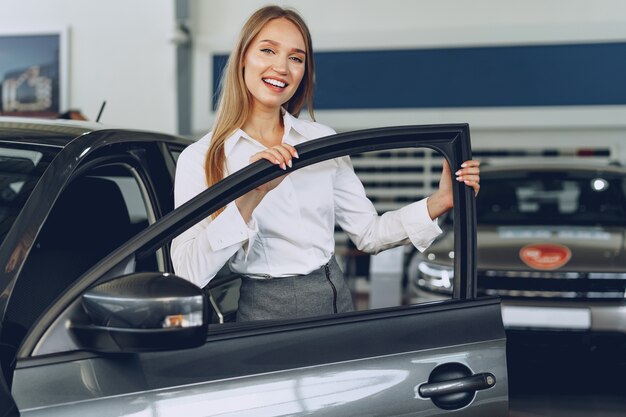 Mooie jonge vrouw haar nieuwe auto met plezier en vreugde aan te raken