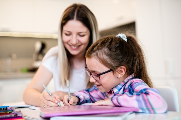 Mooie jonge vrouw helpt haar jongere zus met huiswerk