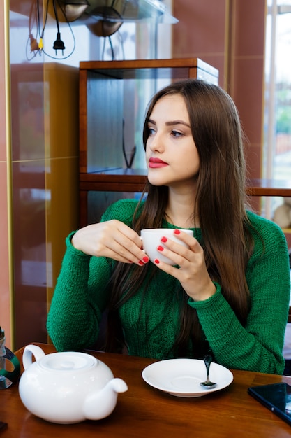 Mooie jonge vrouw het drinken van thee in café