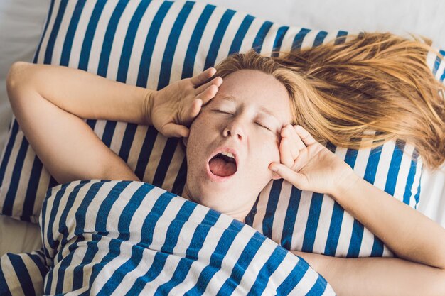 Mooie jonge vrouw in bed liggen en slapen. Krijg niet genoeg slaapconcept