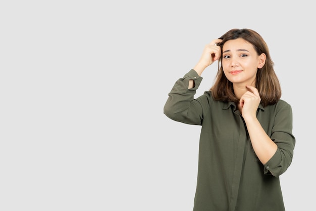 Mooie jonge vrouw in casual outfit staande over witte muur