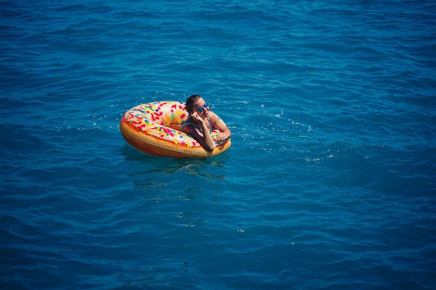 Mooie jonge vrouw in de zee zwemt op een opblaasbare ring en heeft plezier op vakantie Meisje in een helder zwempak aan zee onder het zonlicht