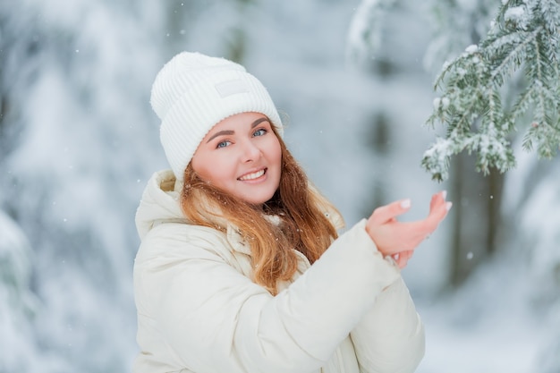 Mooie jonge vrouw in een besneeuwd bos. Vuren takken in de sneeuw. Mooie winter. Winter bos.