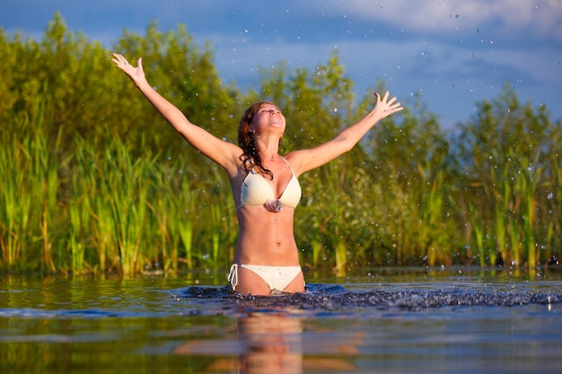 Mooie jonge vrouw in een bikini die bij het meer baden