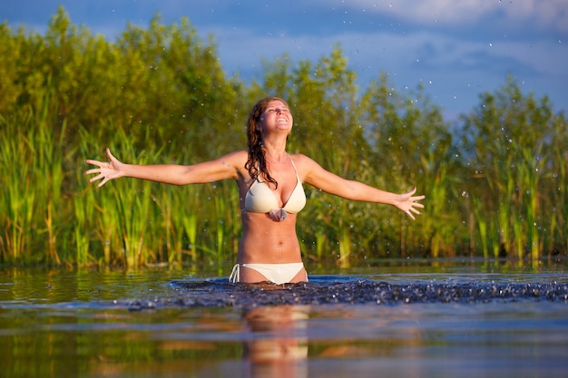 Mooie jonge vrouw in een bikini die bij het meer zwemt..