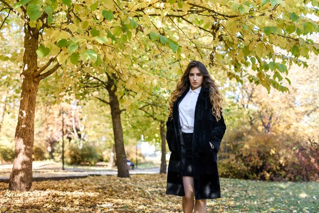 Mooie jonge vrouw in een bontjas in het magische herfstbos.