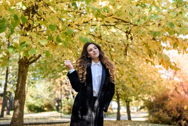 Mooie jonge vrouw in een bontjas in het magische herfstbos.