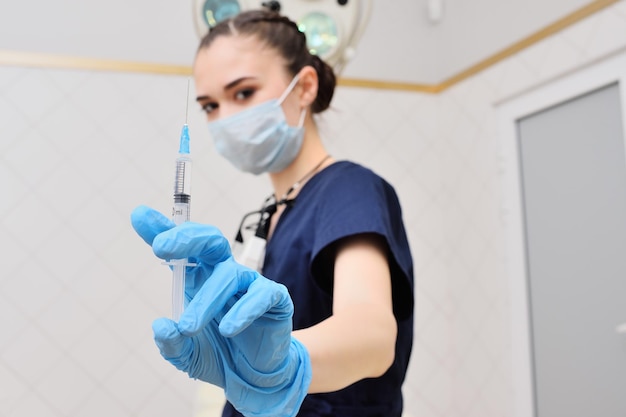 Foto mooie jonge vrouw in een chirurgisch pak in blauwe rubberen handschoenen tegen de achtergrond van een chirurgische lam