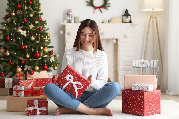 Mooie jonge vrouw in een kerstinterieur met cadeaus voor tekst