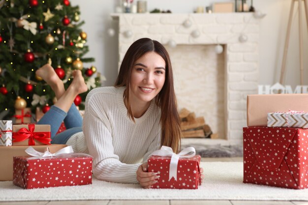 Mooie jonge vrouw in een kerstinterieur met cadeaus voor tekst